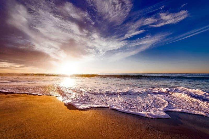 夕焼けと青い空と海を浜辺から撮った写真