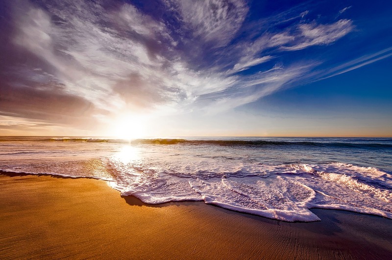 風景で撮られた青空と夕焼けと波が打ち寄せる浜辺の写真