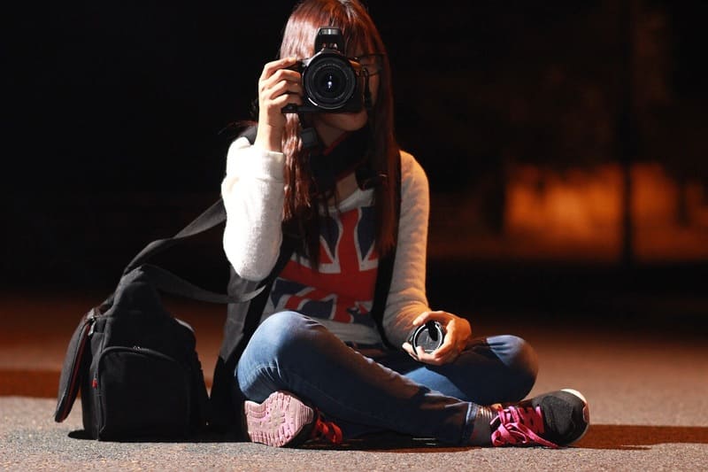 夜中の道路でカメラを構える女性