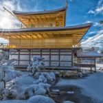 太陽と青空の中の雪の積もった金閣寺